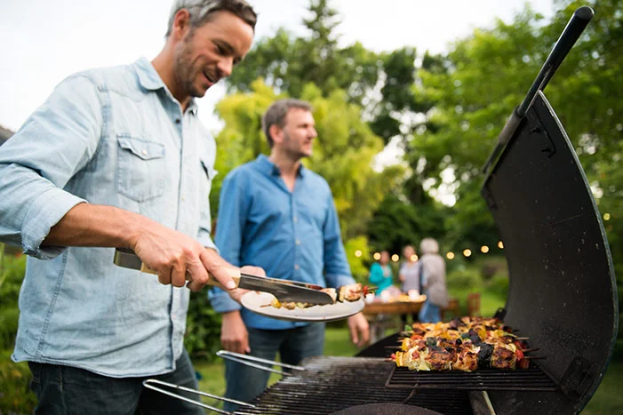 Person grillt Fleisch mit Grillzange